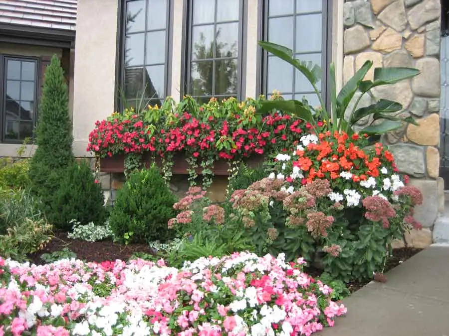 Window box and layered beds of impatiens at a Heritage Hills entry