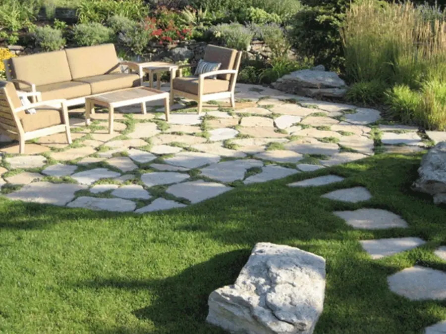 Flagstone patio set in lawn with outdoor seating and ornamental grasses in the Natural Garden