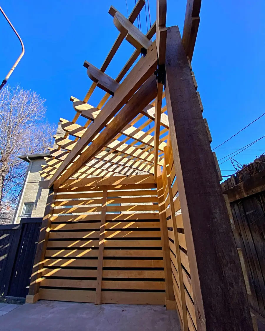 Cedar-toned pergola and privacy screen against a blue sky