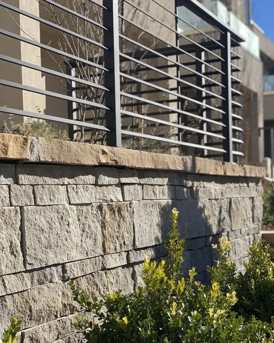 Stacked stone retaining wall with a steel rail